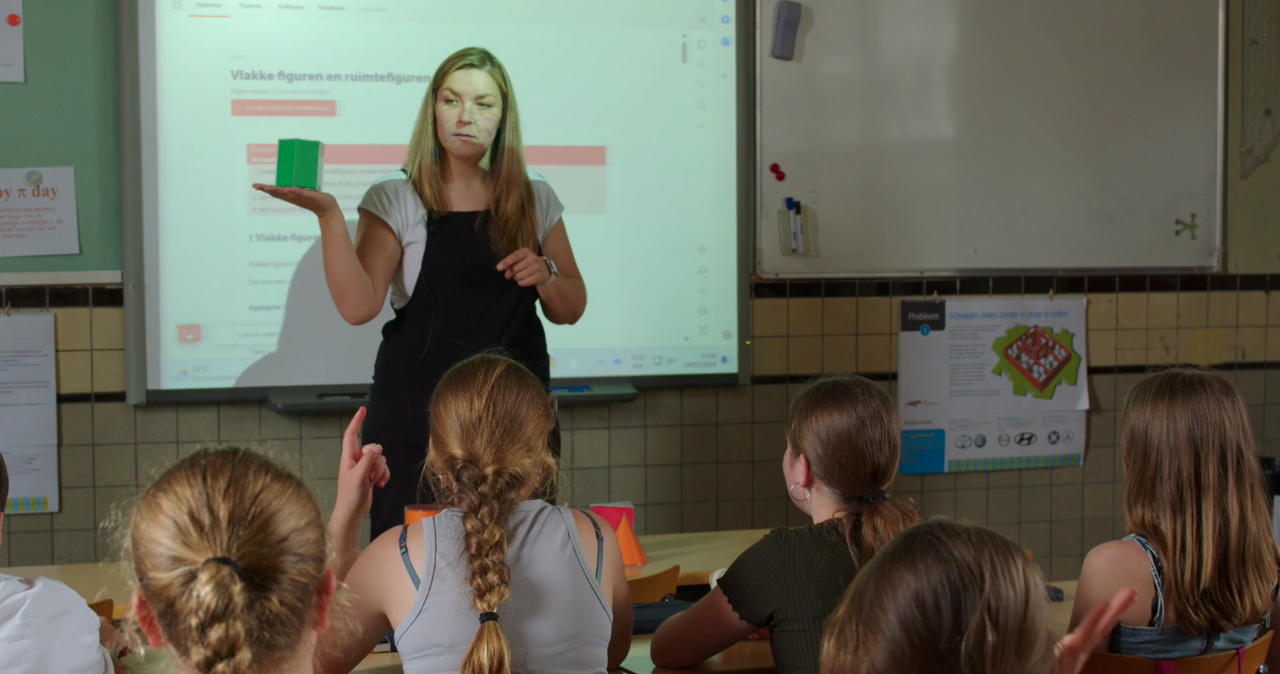 Leerkracht staat voor de klas en geeft klassikale instructie Leerkracht staat voor de klas en geeft klassikale instructie